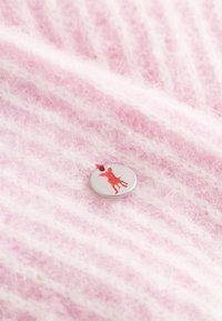 Różowa, paskowana dzianina o miękkiej teksturze z okrągłym, srebrnym guzikiem. Guzik ma wzór w formie czerwonego sylwetki psa.