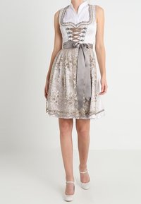 Robe dirndl sans manches avec un corsage blanc à lacets sur le devant, dotée d'une jupe argentée à motifs et d'une ceinture en satin assortie.