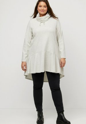 Hellegraue, langärmlige Tunika mit Kapuze, Zugbandsdetail, ausgestelltem Saum und weicher Textur, kombiniert mit schwarzen, figurbetonten Hosen und Stiefeletten.
