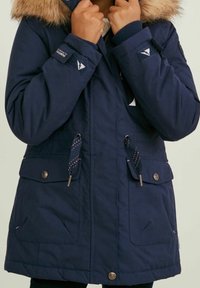 Navy blue parka with faux fur hood, button closures, adjustable drawstrings, and front pockets. Fabric has a smooth texture.