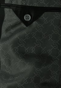 Schwarzer Stoff mit einem dezenten, ineinandergreifenden Muster und einer dreieckigen Klappe, die mit einem schwarzen Knopf mit vier Löchern befestigt ist.