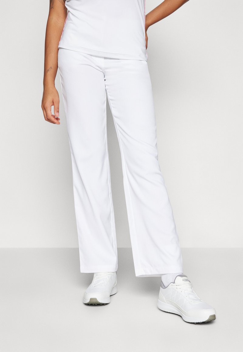 Pantaloni sportivi bianchi con una vestibilità rilassata, tessuto morbido e vita elastica, abbinati a scarpe da ginnastica bianche e a una maglietta leggera.