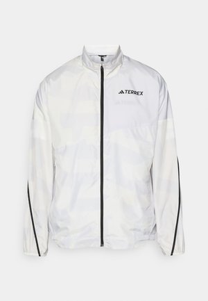 White windbreaker jacket with black accents and a zip closure. Features a high collar and subtle geometric pattern. Logo on the chest.