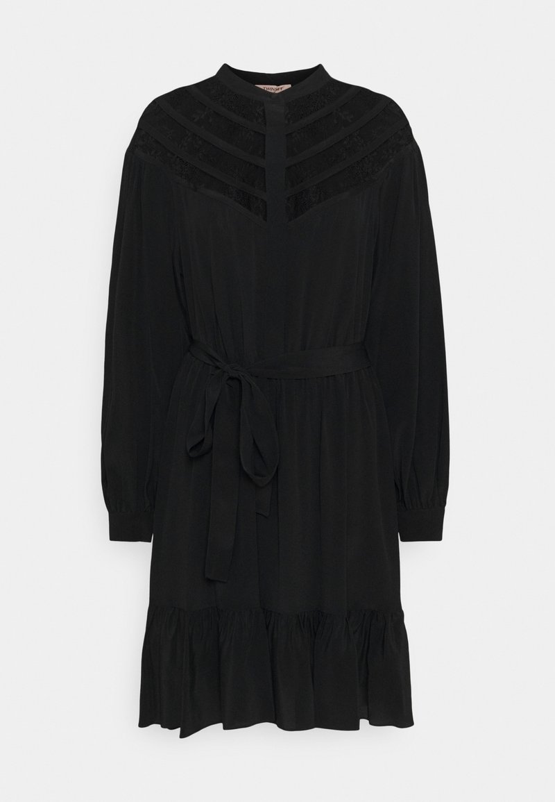 Schwarzes Kleid mit hohem Kragen, langen Ärmeln und einem taillierten Gürtel. Bemerkenswerte Details sind Spitzenakzente und ein gestuftes Rüschensaum.