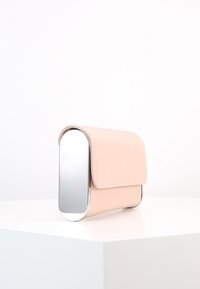 Světle růžové obdélníkové psaníčko s zaoblenými stříbrnými kovovými okraji, ležící na bílém podstavci na bílém pozadí.