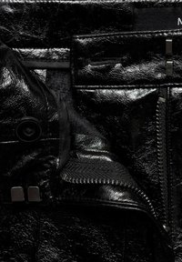 Zwarte faux leren jas met een glanzende textuur. Kenmerken zijn onder andere een rits, drukknoopsluiting en een contrasterende zachte voering.