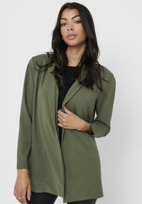 Blazer verde oliva feito de material suave, apresentando uma frente drapeada, mangas longas e uma silhueta descontraída. Sem fechos ou padrões visíveis.