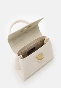 Mała beżowa skórzana torebka z zapięciem w złotym odcieniu, teksturowany powierzchnia, usztywniony kształt oraz miękka tkaninowa podszewka z metką marki.