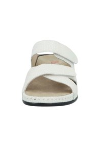 White sandal featuring a textured upper with two wide straps crossed over an open toe. Soft beige footbed and black rubber sole.