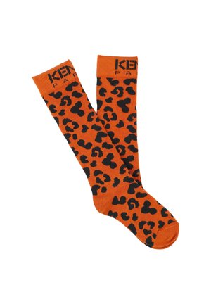 Chaussettes montantes orange vif avec un motif léopard noir. Présente une finition texturée et un logo tricoté en haut.