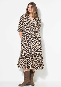 Leopardenmuster Midi-Kleid in Beige und Schwarz, mit durchgehender Knopfleiste, langen Ärmeln und einem ausgestellten Rüschensaum. Getragen mit braunen Cowboy-Stiefeln.