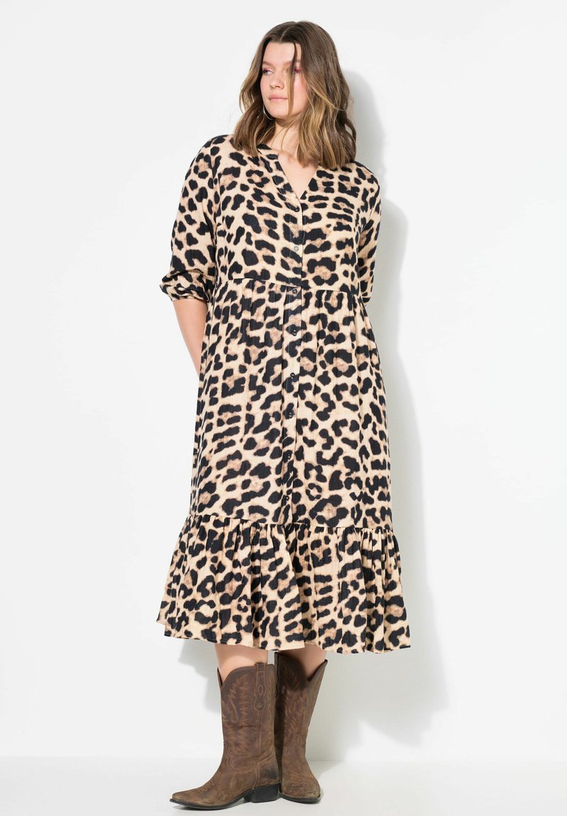 Leopardenmuster Midi-Kleid in Beige und Schwarz, mit durchgehender Knopfleiste, langen Ärmeln und einem ausgestellten Rüschensaum. Getragen mit braunen Cowboy-Stiefeln.