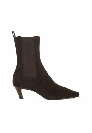 Bottine noire en suede, à bout pointu et petit talon. Comprend des panneaux élastiques sur les côtés pour un enfilage facile. Texture lisse avec un design minimaliste.