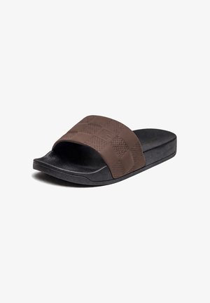 Schwarze Slide-Sandale mit dickem, strukturiertem braunem Riemen mit Schachbrettmuster und geprägtem Logo auf weißem Hintergrund.