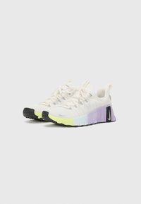 Sneakers met een witte bovenkant, lichtgewicht textiel en een gelaagde zool in pastelgradiënt van geel naar paars; zwarte rubberen buitenzool.
