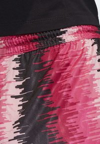 Černé a růžové sportovní šortky mají texturovaný, abstraktní vzor v odstínech růžové, černé a světle růžové a elastický pas.