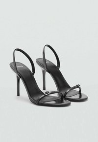 Zwarte hoge hakken sandalen met een slank ontwerp, voorzien van dunne bandjes, een gespaccent en een gladde gepolijste leren textuur.
