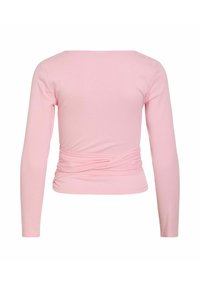 Μπλούζα με μακριά μανίκια, ανοιχτό ροζ, με ντεκολτέ σε σχήμα βάρκας και δομή από στριμμένο ύφασμα γύρω από τη μέση, εμφανίζεται από πίσω.