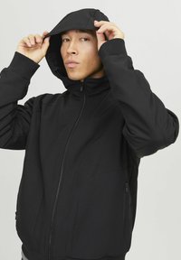 Schwarze Kapuzenjacke mit Reißverschluss, strukturiertem Stoff, Seitentaschen und verstellbarem Kordelzug an der Kapuze. Lässige Passform mit nahtlosem Design.
