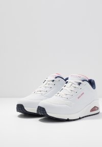 Bílé tenisky Skechers s prodyšným síťovaným svrškem, námořnickými akcenty a vzorovanou gumovou podešví. Obsahují viditelné vzduchové polstrování v patě.