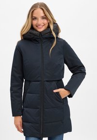 Wollen pufferjas in donker marineblauw, met een hoge kraag, ritssluiting aan de voorkant en zijzakken. Gequilt textuur met een getailleerde taille en een middelhoge snit.