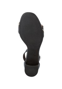 Suola di sandalo con tacco nero, caratterizzata da un motivo in gomma testurizzata antiscivolo, tacco largo e un accento metallico vicino alla cinghia della caviglia.