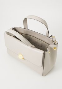 Sac à main en cuir gris clair avec une forme structurée, une poignée supérieure et un fermoir doré. L'intérieur comprend une poche zippée et une étiquette de marque.