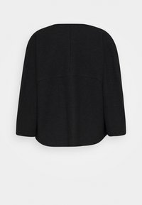 Černý top s dlouhým rukávem, který má volný střih a zakulacený lem. Vyrobeno z texturované tkaniny, se švy na zadní straně.