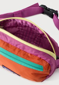 Συμπαγής τσάντα μέσης με μωβ λουράκι, ανοιχτό κίτρινο φερμουάρ στο κύριο τμήμα, πορτοκαλί μπροστινή περιοχή και τσέπη με τουρκουάζ φερμουάρ μπροστά.