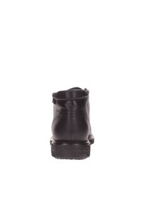 Botte chelsea en cuir noir avec un bout arrondi, semelle en caoutchouc texturé et un design simple. Présente des coutures minimales et un petit talon.