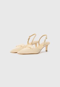 Beige Slingback-Absätze mit spitzen Zehen, die mit einer goldenen Kettenakzentuierung auf dem Blatt und einem moderaten Absatz versehen sind. Aus glattem Leder.