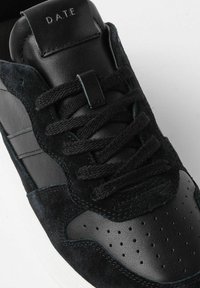 Sneaker nera caratterizzata da un mix di suede e pelle, con accenti testurizzati, punta perforata e lacci neri piatti. Logo D.A.T.E. sulla linguetta.