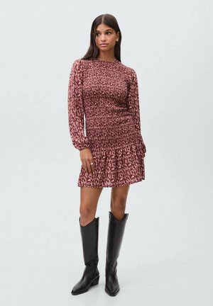 Vestido corto con diseño fruncido en color burdeos con un estampado floral, mangas largas y dobladillo acampanado. Combinado con botas negras hasta la rodilla.
