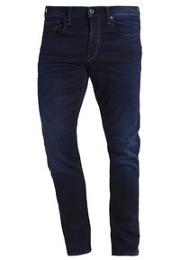 Tmavě modré džíny z denimu s úzkým střihem, pěti kapsami, mírným vyblednutím na stehnech a kovovými detaily.