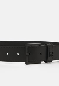 Ceinture en cuir noir avec une texture lisse, boucle en métal rectangulaire et petits trous d'ajustement. Comprend un logo sur la boucle en cuir.