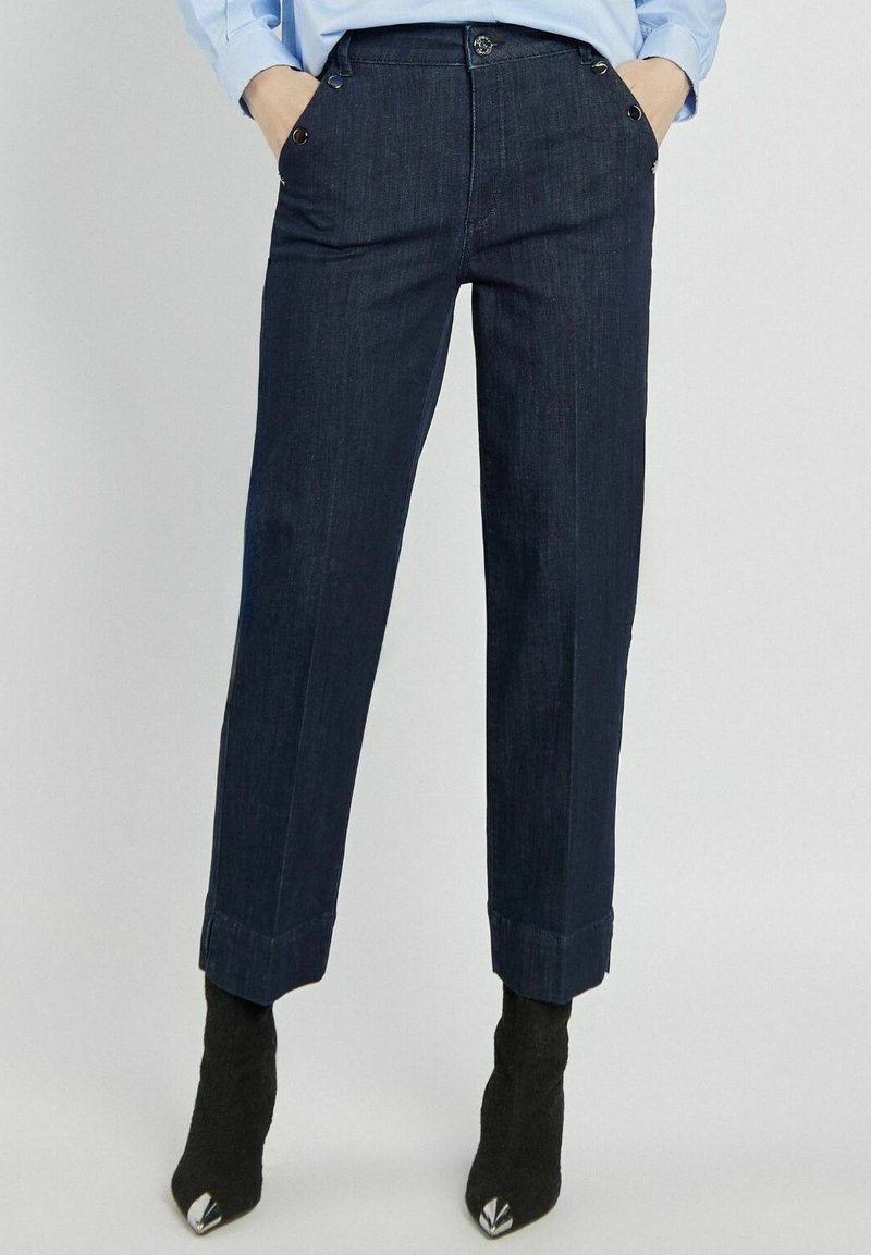 Granatowe dżinsy o prostym kroju, z kieszeniami z przodu, mankietami i złotym wykończeniem.