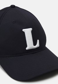 Granatowa czapka baseballowa z materiału, z wyraźnym białym haftowanym "L" z przodu i zaokrąglonym daszkiem.