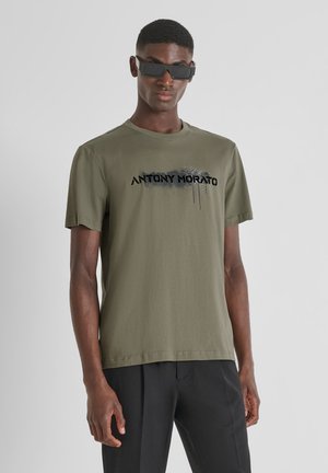 Camiseta de algodón verde oliva con mangas cortas y cuello redondo, con el texto impreso en negro "ANTONY MORATO" y un diseño de efecto salpicado.