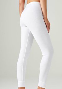 Leggings blancos confeccionados en tejido elástico, con un ajuste ceñido, cinturilla elástica y puños acanalados, que destacan por su textura suave y diseño minimalista.