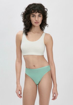 Bra sportivo grigio chiaro con spalline larghe, texture liscia; abbinato a slip hipster verde menta con una vita morbida.