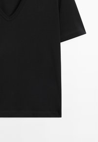 Sort kortærmet V-hals T-shirt med synlige sømme på ærmerne og kanten mod en hvid baggrund.