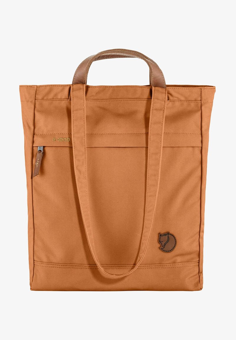 Tote taske i orange G-1000 stof, med to håndtag, forlommer og et læderlogo. Glat tekstur med robust design.