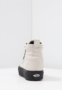Beige Leder High-Top Sneaker mit strukturiertem Finish, schwarzen Schnürsenkeln und schwarzer Sohle. Verfügt über eine Logo-Plakette an der Ferse.