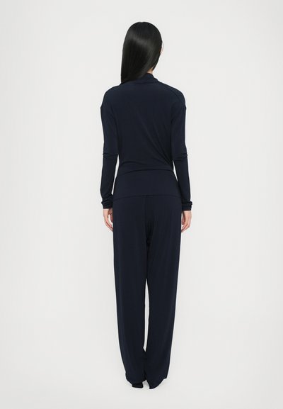 Navy two-piece lounge set featuring a long-sleeve top and wide-leg pants, made from a soft, smooth fabric with a relaxed fit.