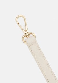 Beige leren band met een gestructureerde afwerking, voorzien van een goudkleurige kreeftenhaak en een cirkelvormige bevestigingsring.