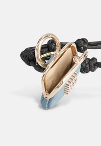 Sac compact en cuir bleu clair avec quincaillerie dorée, doté d'une fermeture à boucle, d'un intérieur texturé et d'une sangle noire tressée.