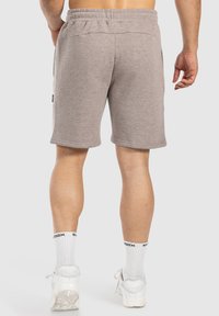 Pantalones cortos de algodón gris claro con una cintura elástica, dos bolsillos laterales y una longitud a mitad del muslo, que exhiben una textura suave.