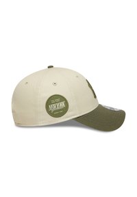 Cappellino da baseball color khaki con visiera verde oliva. Presenta il logo ricamato dei New York Yankees sul davanti e una toppa circolare di lato.