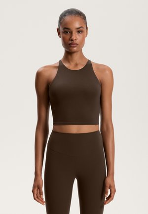 Brun crop top med høj hals, lavet af et glat, strækbart materiale. Kombineret med højtaljede matchende leggings.