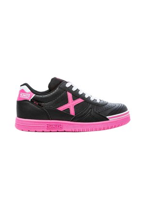Zapatilla negra de corte bajo con cordones blancos, suela y detalles de color rosa brillante, y un "X" rosa en el lateral con el nombre de la marca "Munich."